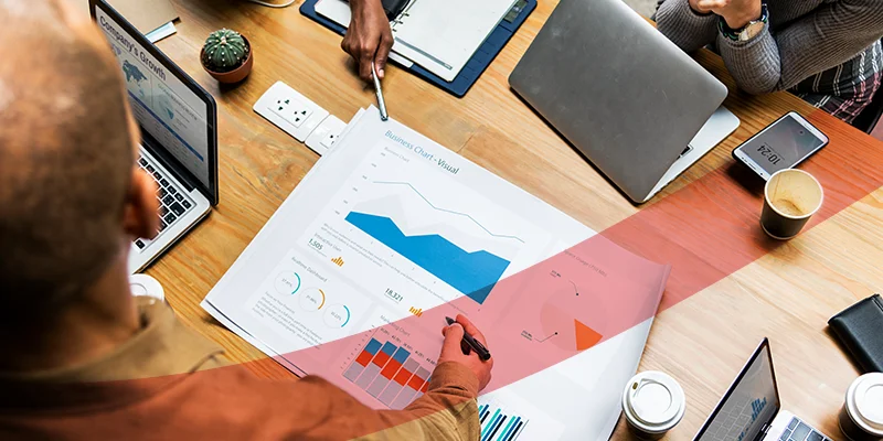 Equipe de negócios analisando gráficos e dados em reunião com laptops e documentos, ilustrando um artigo da Siteware sobre a Matriz Ansoff.