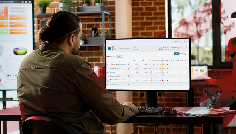 Profissional analisando o painel de resultados do Stratws One em um monitor, com gráficos e indicadores de desempenho exibidos na tela, em um ambiente de escritório moderno.
