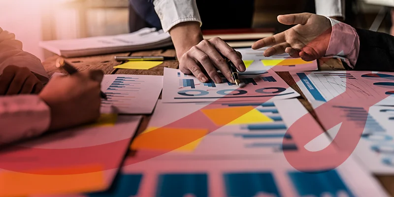 Análise de gráficos e dados financeiros em reunião de negócios com pessoas discutindo estratégias, ilustrando um artigo sobre planejamento estratégico da Siteware.