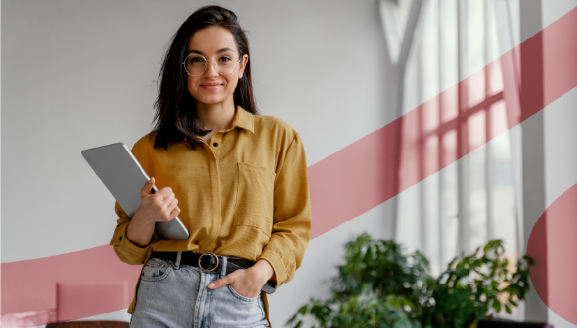 Mulher jovem sorridente com óculos, vestida de camisa amarela e jeans, segurando um dispositivo portátil em um ambiente moderno de escritório. Imagem usada como capa no artigo "Remuneração Variável na CLT".