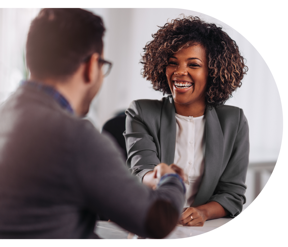 Mulher negra sorridente cumprimentando homem em ambiente profissional, simbolizando conexão e networking de negócios.