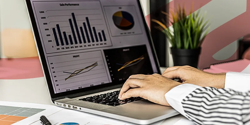 Pessoa digitando em laptop com gráficos de desempenho de vendas e lucro na tela, ilustrando um artigo da Siteware sobre KPIs de vendas.