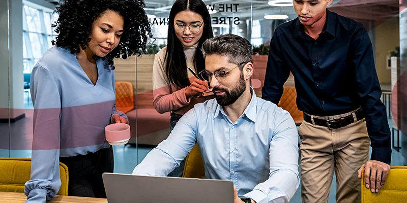 Equipe diversificada colaborando em escritório moderno, ilustrando um artigo da Siteware sobre a metodologia dos 5 porquês.