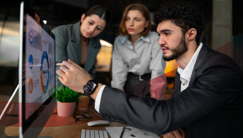 Três profissionais analisando gráficos e indicadores estratégicos em um monitor, representando o uso conjunto de KPIs e OKRs no acompanhamento de resultados corporativos.