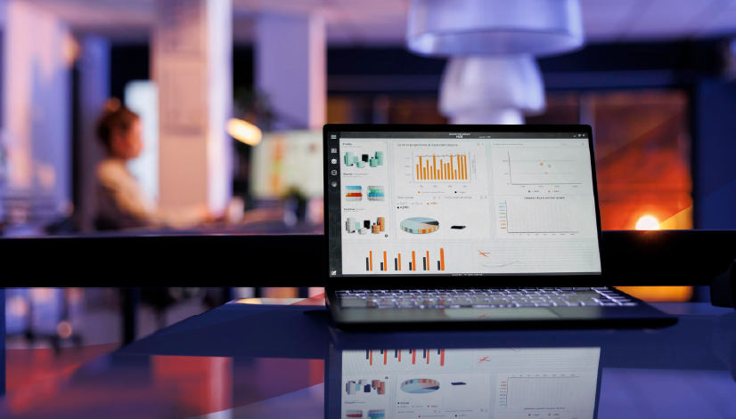 Notebook com dashboard de indicadores e gráficos do painel de indicadores do Stratws aberto sobre mesa em escritório com iluminação ambiente. A imagem representa o uso do Stratws conectado via IA (MCP) para gestão estratégica.